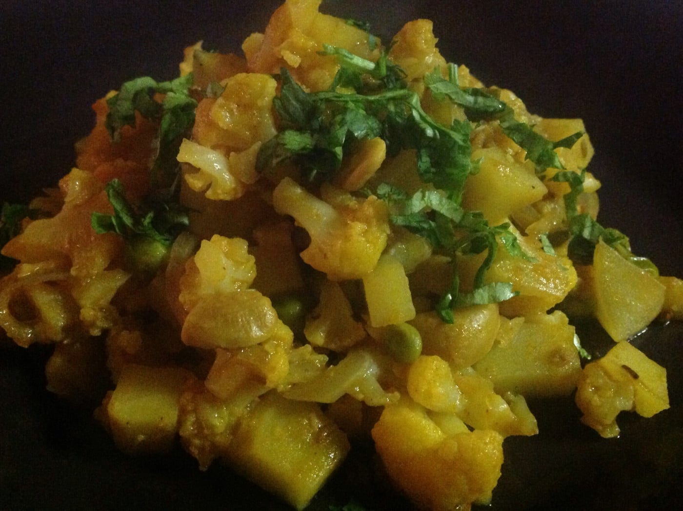 Closeup view of cauliflower and potato curry on a black plate