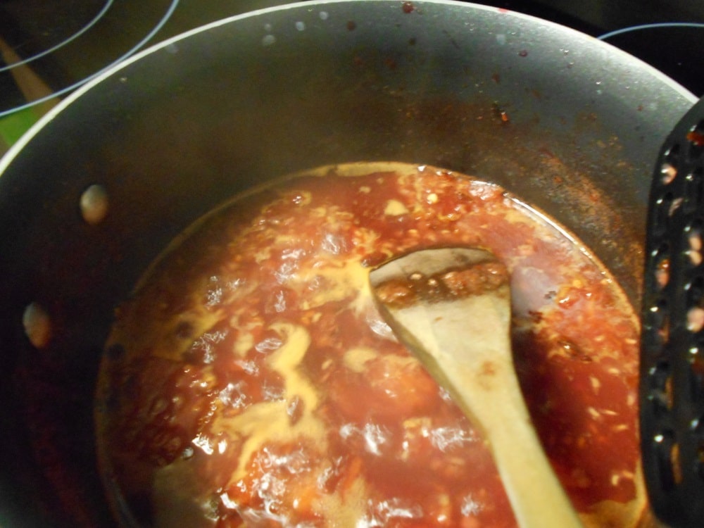 View of a saucepan with the contents of tomato jam boiling