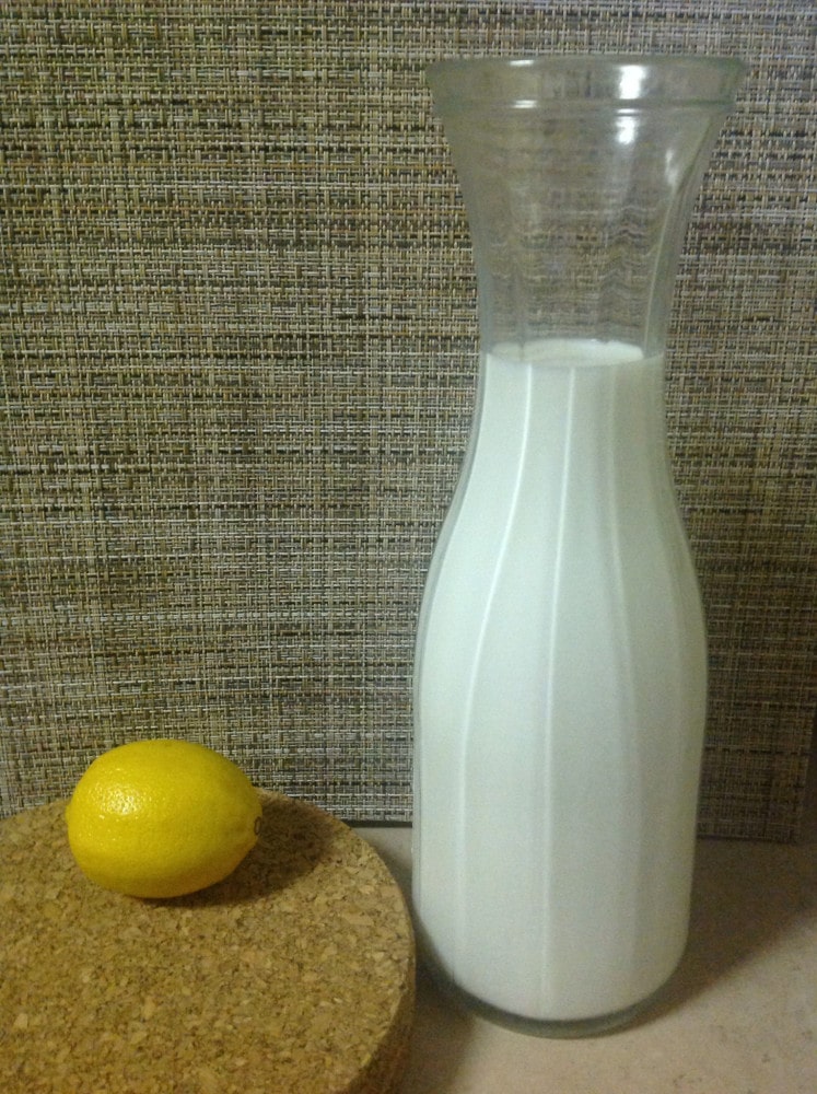 Front view of the 2 ingredients needed in this recipe: Glass bottle filled with milk and one whole lemon