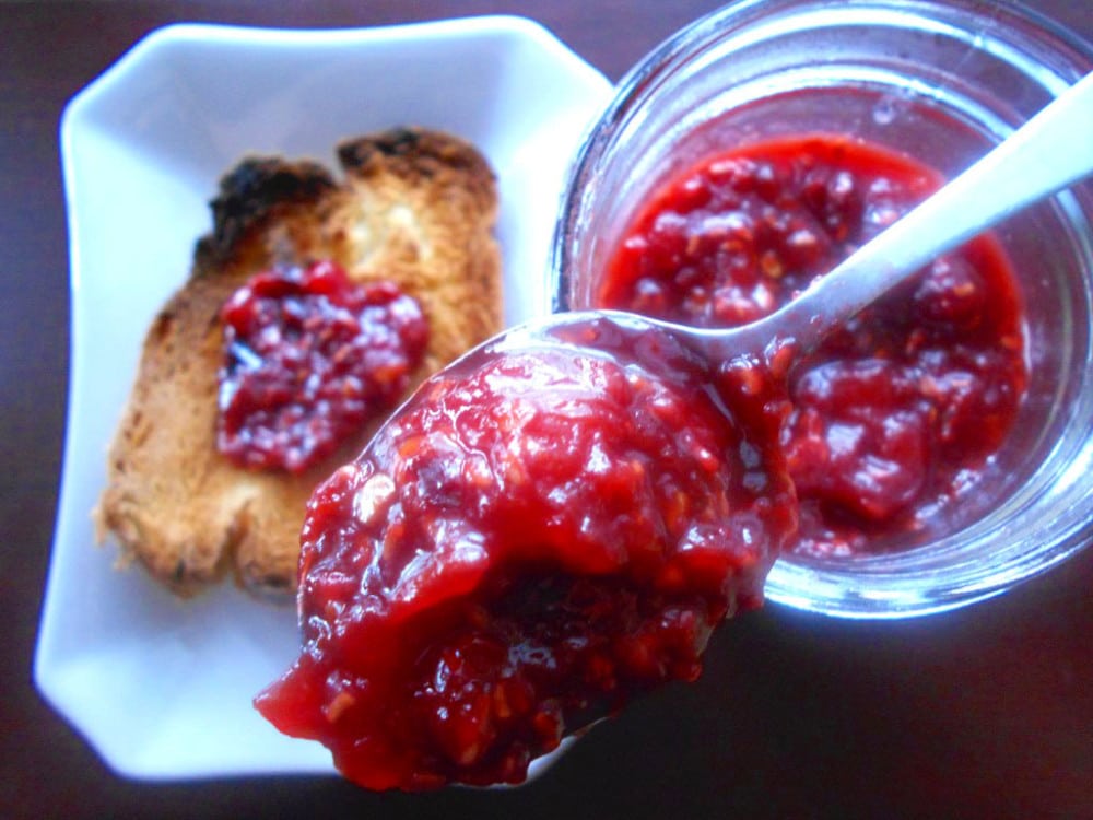 Overhead view of a spoon resting on a mason jar. Spoon is filled with the tomato jam