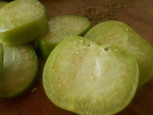 Sliced green tomatillo and carom seeds