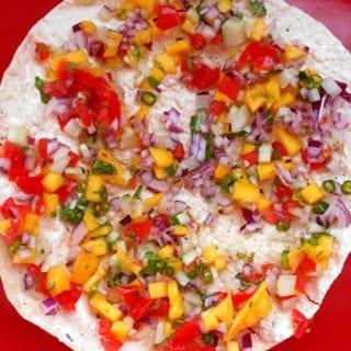 Closeup View of A Square Red Plate with Papad Cut into Quarters and Topped with Mango, onions and Red Peppers