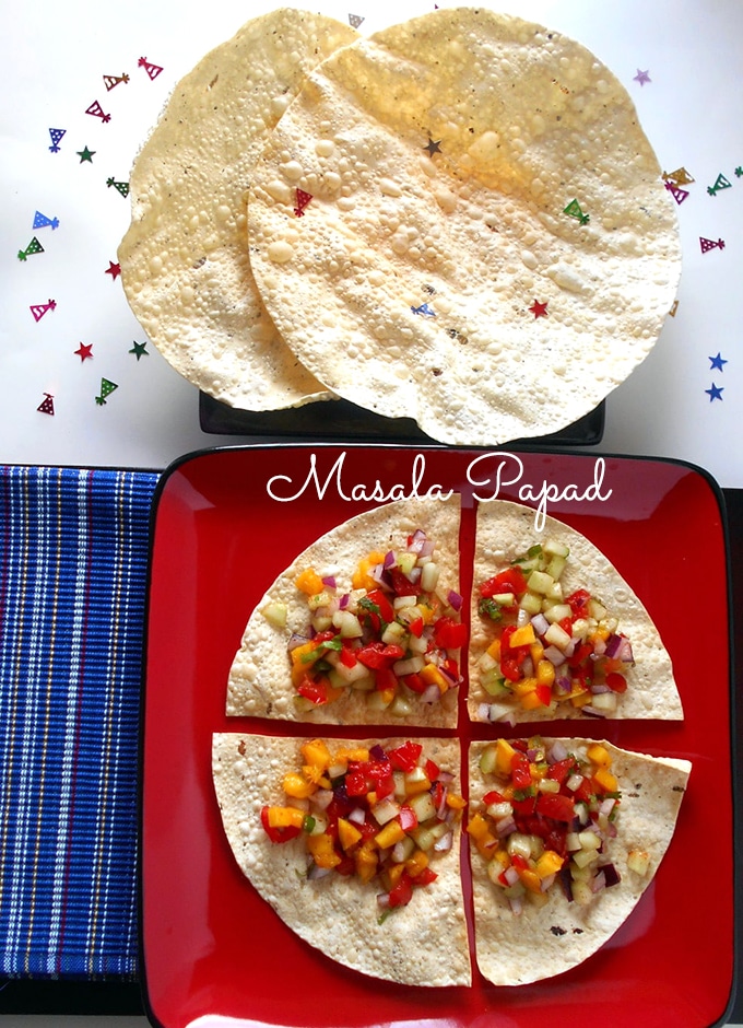 Overhead View of A Square Red Plate with Papad Cut into Quarters and Topped with Mango, onions and Red Peppers