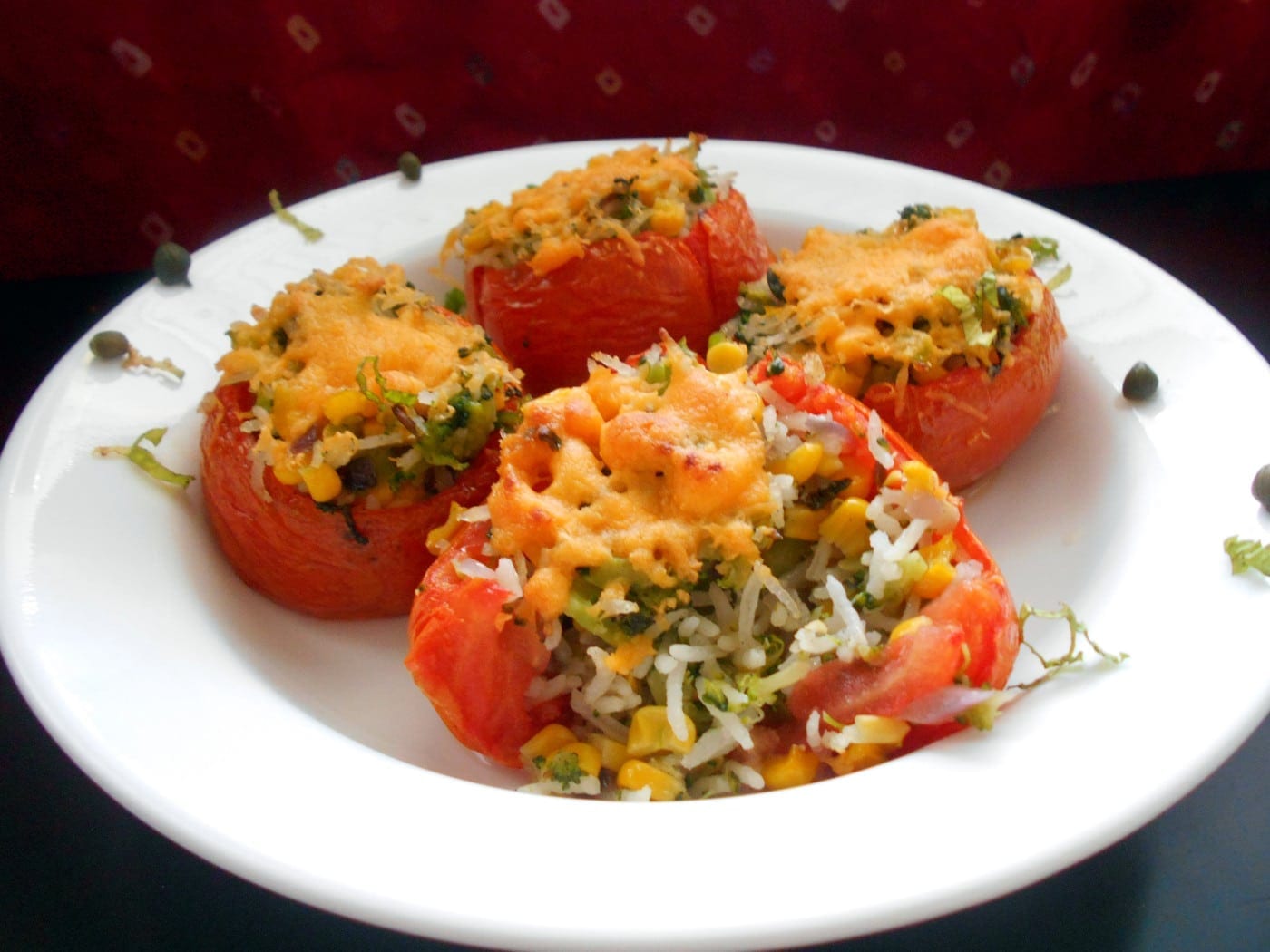 Cooked Stuffed Tomatoes on a white plate with garnish