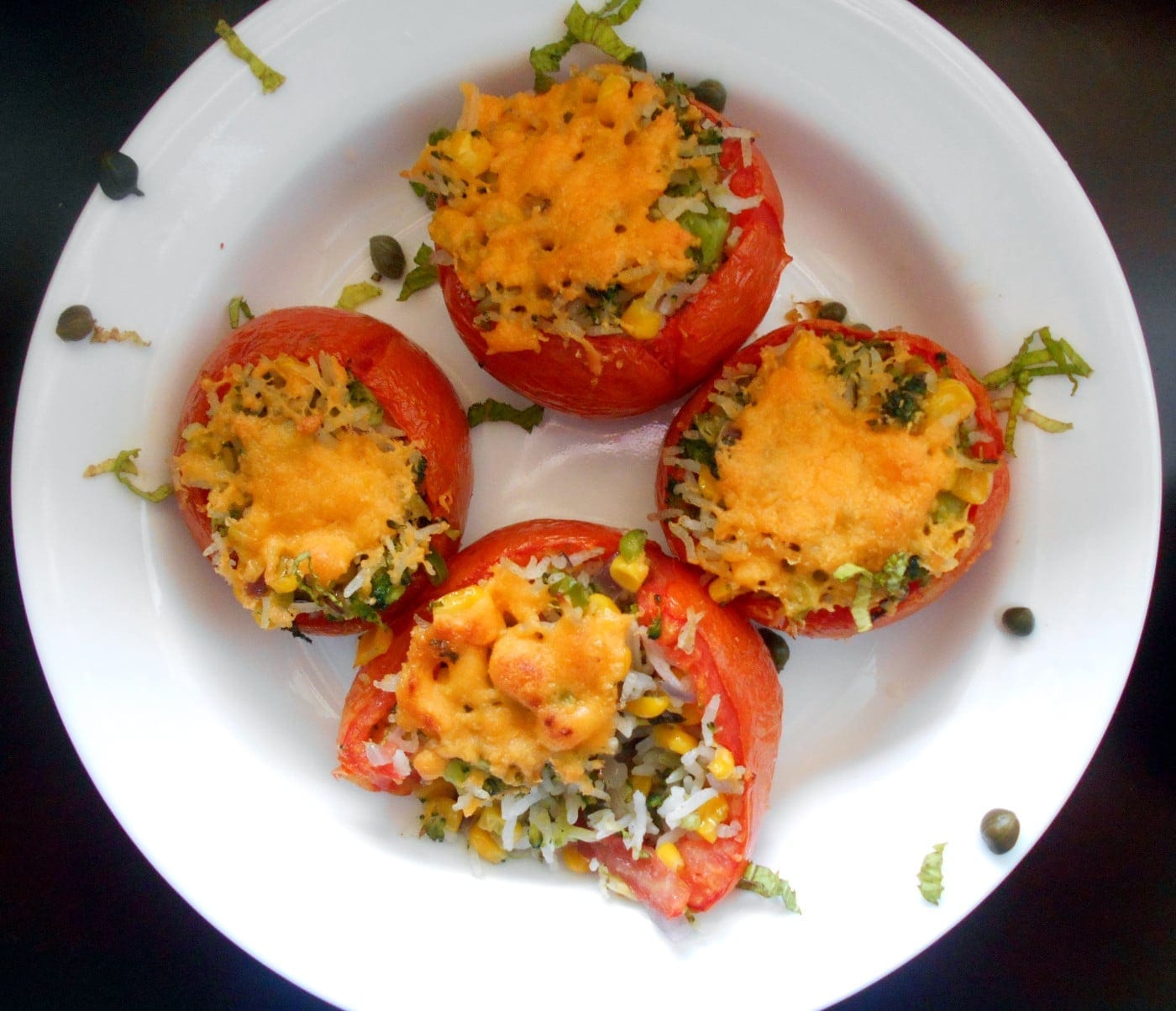 Cooked Stuffed Tomatoes on a white plate with garnish
