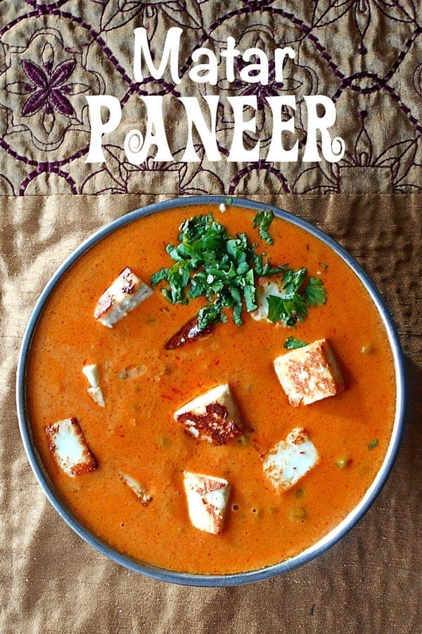 Overhead view of a thick, creamy tomato sauce with roasted paneer and peas
