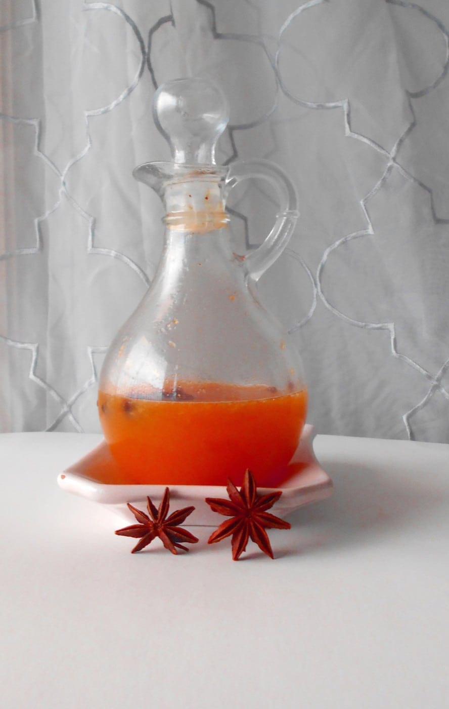 Front view of Orange Dressing in a dressing glass bottle. 2 Star anise are in front of it