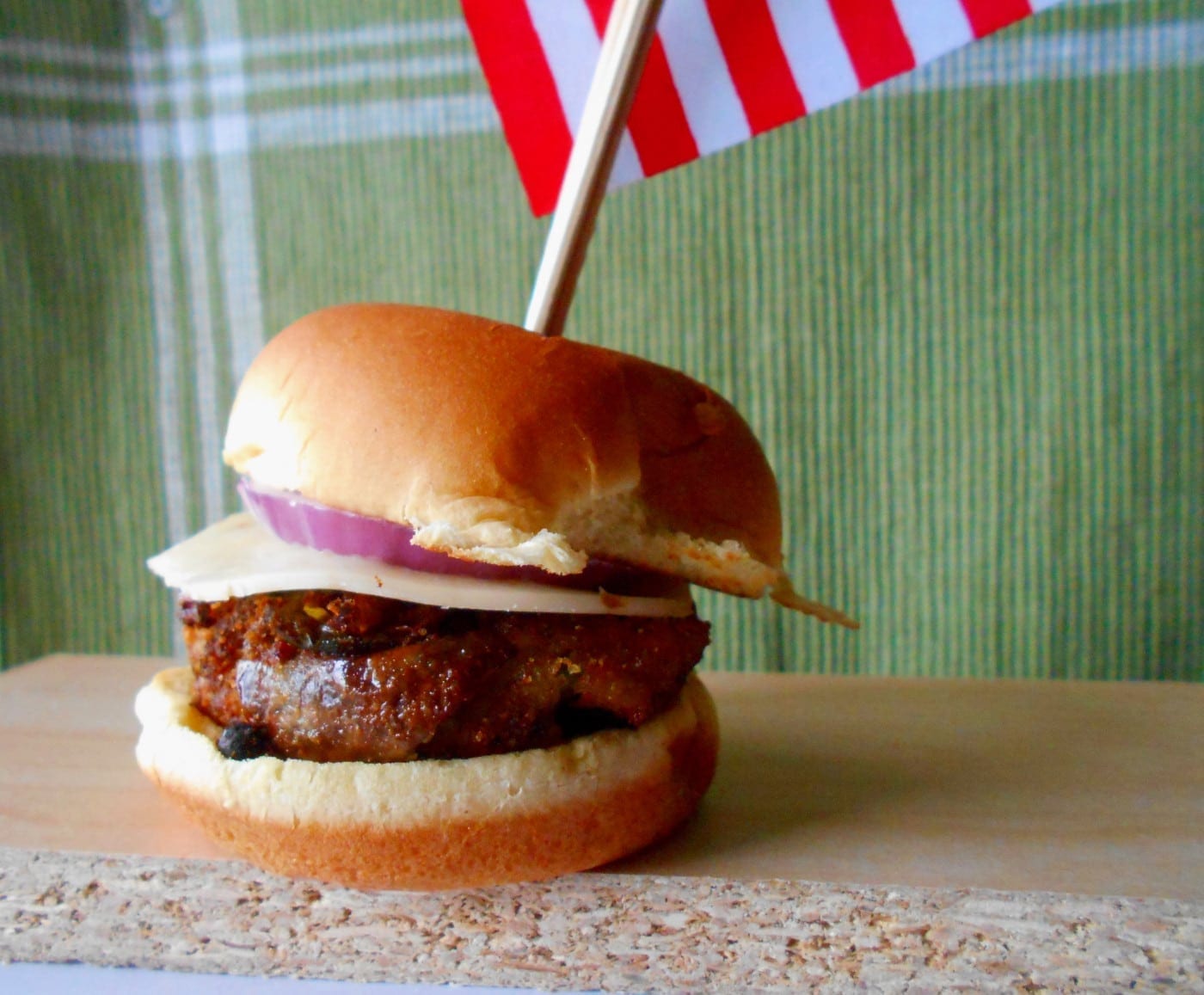 Front view of a veggie burger recipe on a brown board with an American flag toothpick and a football field background