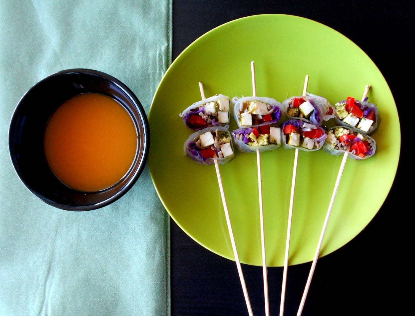 Top view of vegetarian rolls on sticks with apricot dressing on the side