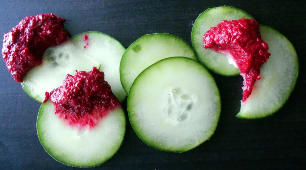 Cucumber rounds dipped in beet hummus