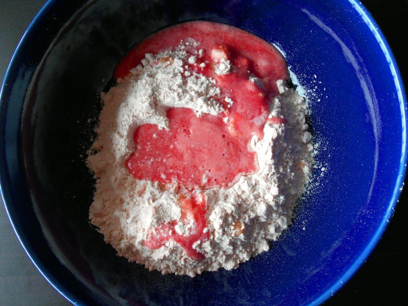 Overhead view of a blue bowl filled with flour and pureed tomato