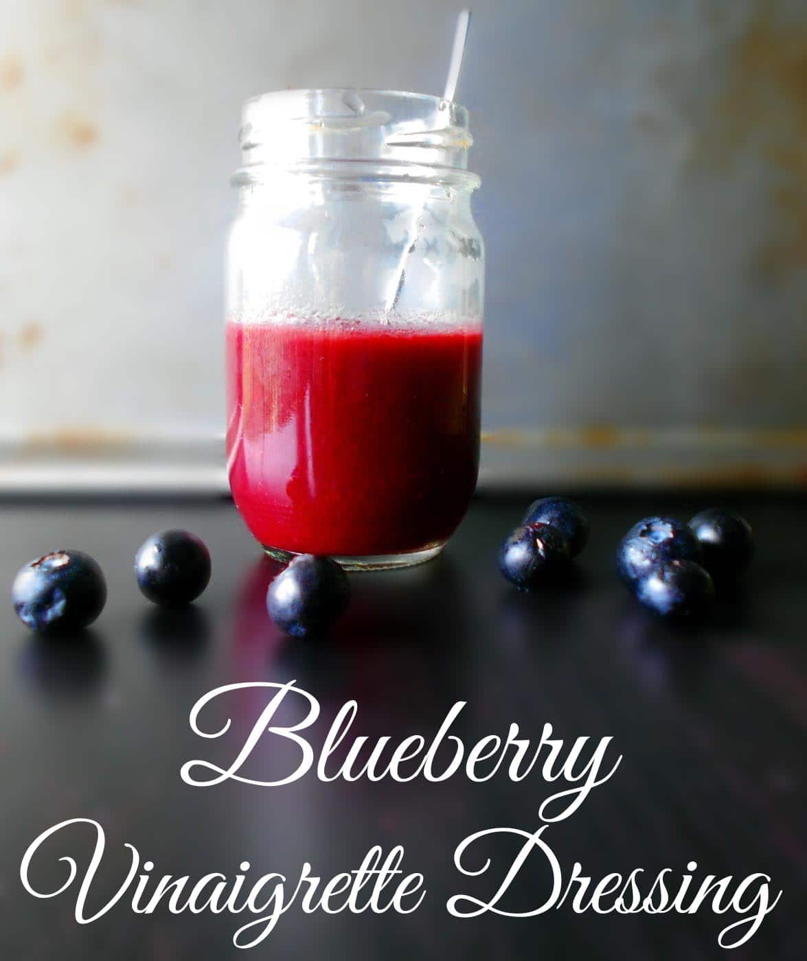 Front view of a glass bottle with Blueberry Vinaigrette surrounded by blueberries