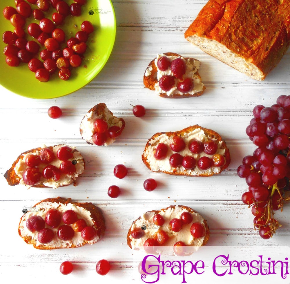 Overhead view of several grape crostinis with a bunch of grapes on the side