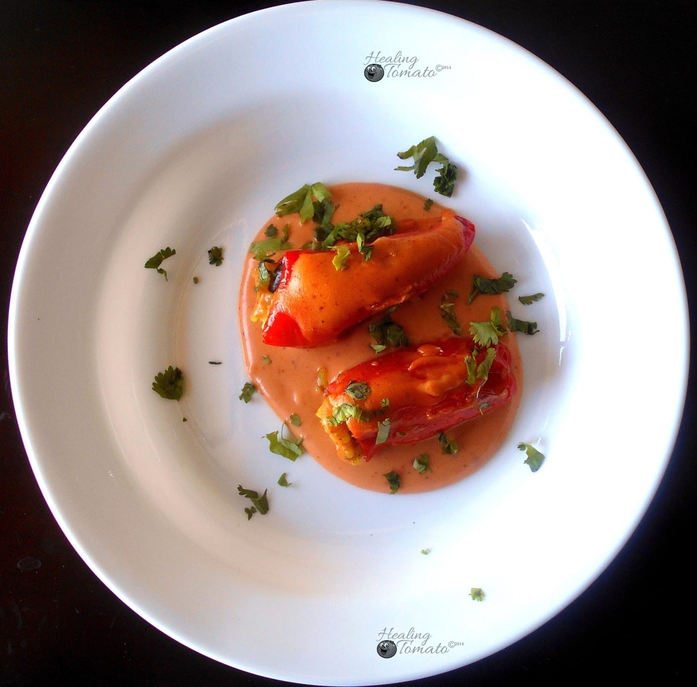 Top view of 2 mini sweet peppers stuffed with mexican flavors over creamy enchilada sauce