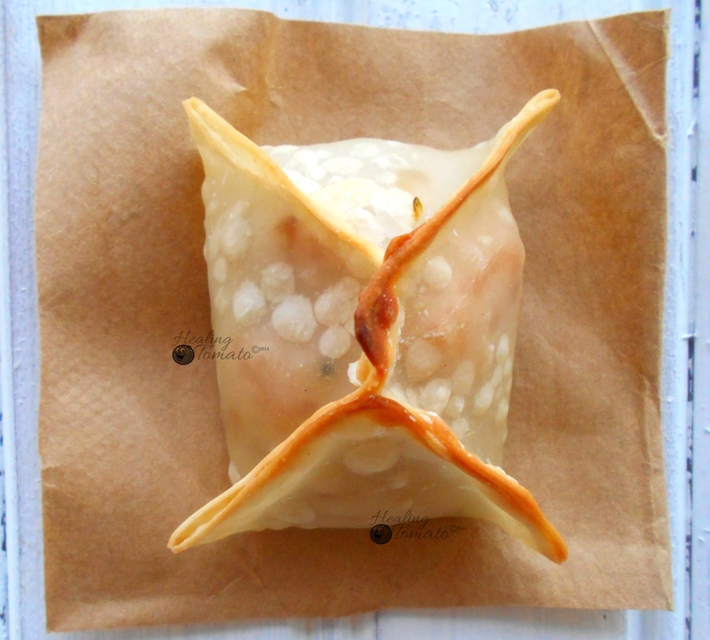 Overhead view of a samosa wonton on a brown piece of paper