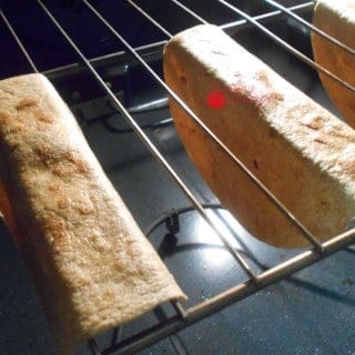 Oven View of 2 Done Tortillas Hung Upside Down in the Rails of Oven Racks