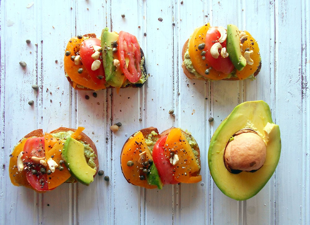 Avocado toast made with Pina Colada Guacamole, tomatoes and capers. This is perfect if you are looking for a quick brunch meal or a quick snack.