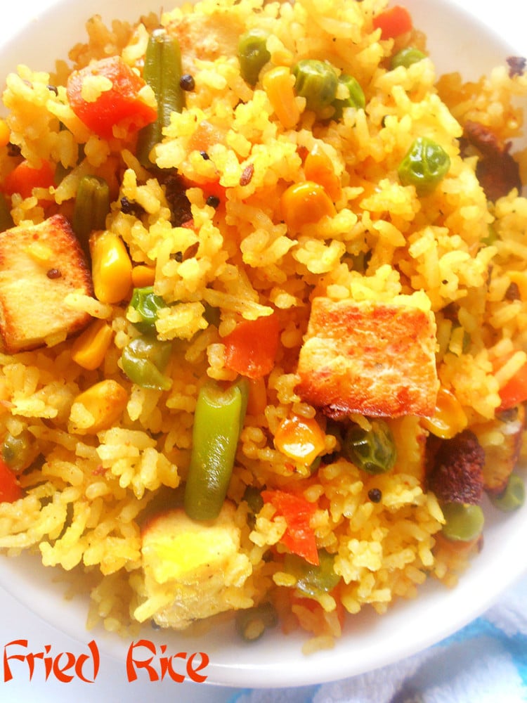 Overhead view of a bowl of vegan fried rice with vegetbles. Fork on the side