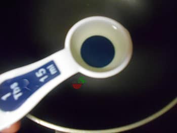 Overhead view of a 1 Tbsp of measuring spoon filled with oil