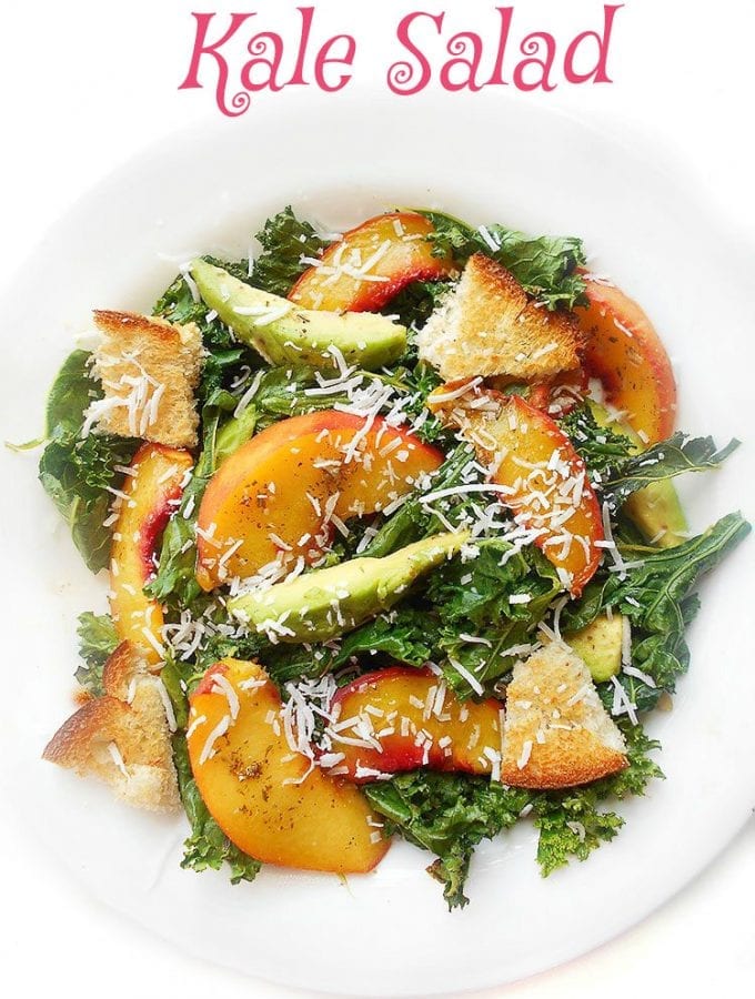 Overhead view of Kale salad with peaches, avocado and coconut shavings on a white plate