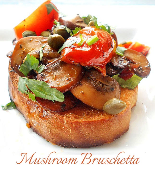 Angle view of a small baguette size topped with mushrooms, capers, and tomatoes.  