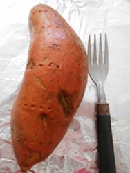 A thouroughly cleaned sweet potato with holes pocked in it is on a foil with a fork next to it - 5 Tips on Baking The Perfect Sweet Potato