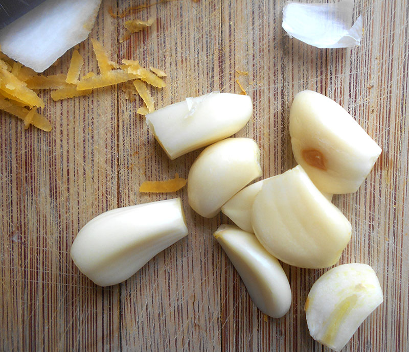 Peeled and halved garlic on a chopping board