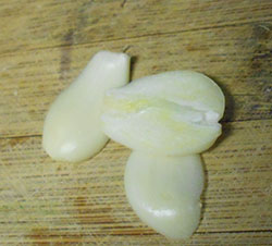 Peeled and thinly sliced garlic on a brown chopping board