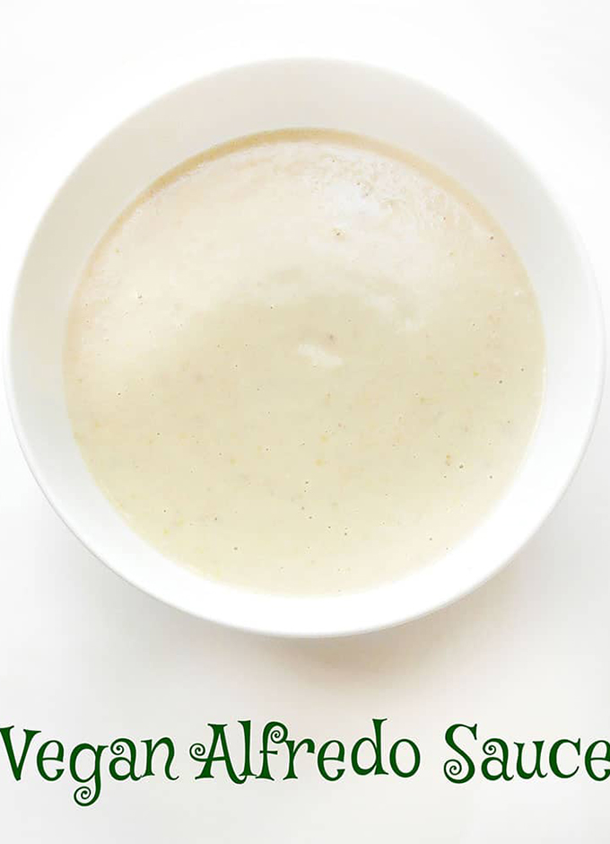 Overhead View of a White Bowl Filled with Creamy Vegan Alfredo Placed on a White Background