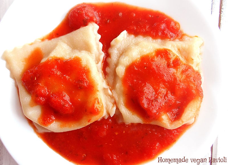 Overhead view of 2 cooked ravioli on a white plate with marinara sauce