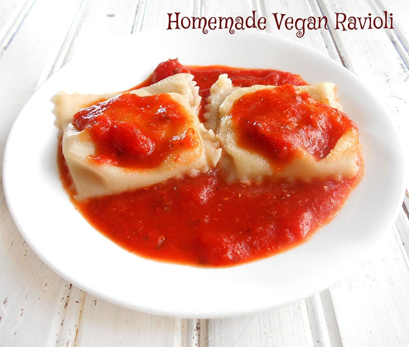 side view of 2 cooked ravioli on a white plate topped with marinara sauce
