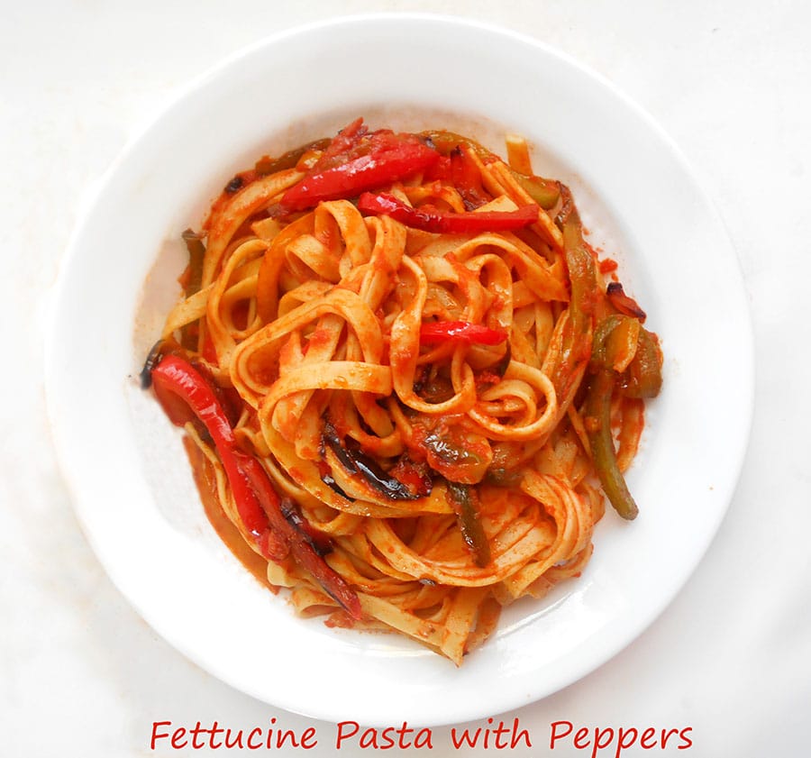 Closeup view of fettuccine pasta and roasted bell peppers in a red marinara sauce