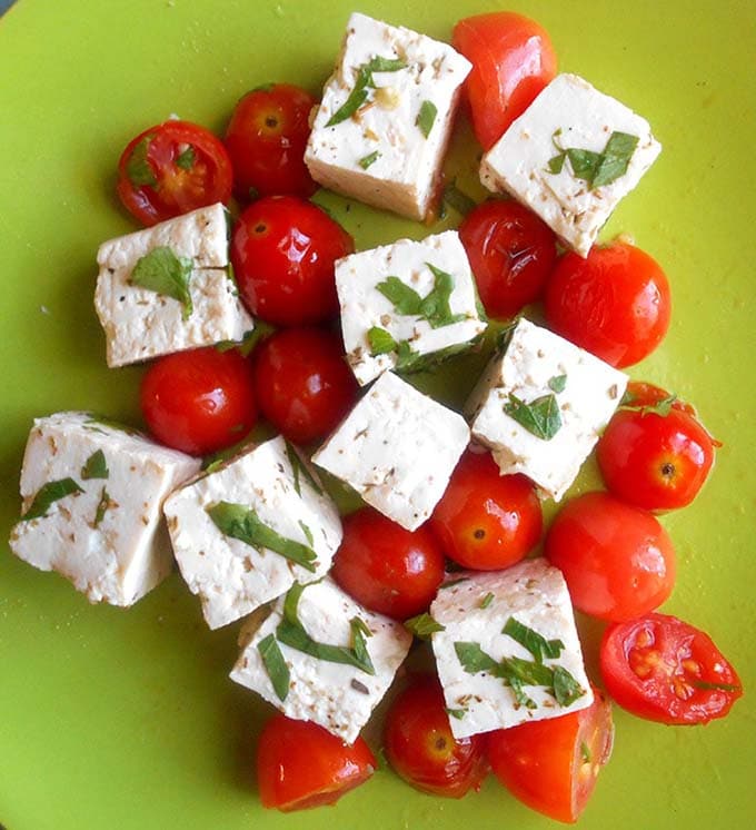 Tofu cubes with cherry tomatoes and cilantro garnish on a green plate