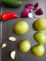 Tomatillos, garlic, peppers and red onions on a baking tray