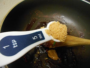 1 Tbsp measuring spoon filled with brown sugar over a stir fry pan - Vegan Pad Thai Recipe