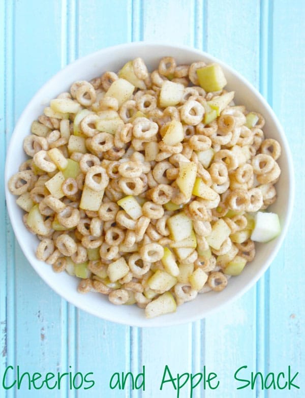 Overhead view of a bowl of cheerios and apples on a blue background