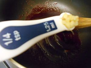 1 Tbsp measuring spoon filled with chopped garlic over a stir fry pan - Vegan Pad Thai Recipe