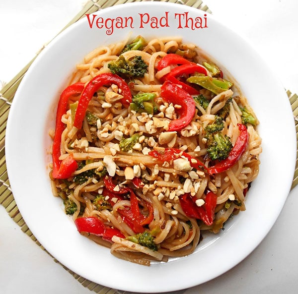 Overhead view of a white plate with cooked rice noodles, bell pepper and broccoli in Pad Thai. Peanuts serve as garnish - Pad Thai Recipes