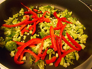 Overhead view of broccoli and red bell peppers cooking in a frying pan - Vegan Pad Thai Recipe
