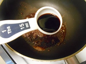 1 Tbsp measuring spoon filled with soy sauce over a stir fry pan - Vegan Pad Thai Recipe