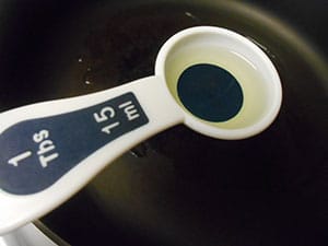 1 Tbsp measuring spoon filled with oil over a stir fry pan - Vegan Pad Thai Recipe