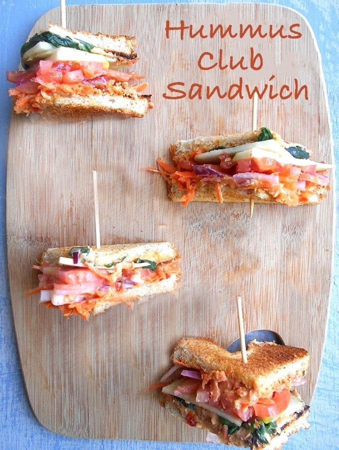 Overhead View of 4 Club Sandwiches Cut into Triangle Shapes Sitting on a Brown Cutting Board.