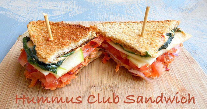 Overhead View of 2 Club Sandwiches Cut into Triangle Shapes Sitting on a Brown Cutting Board.