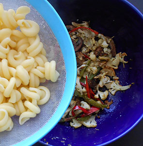 cooked tortolle pasta being added to the bowl