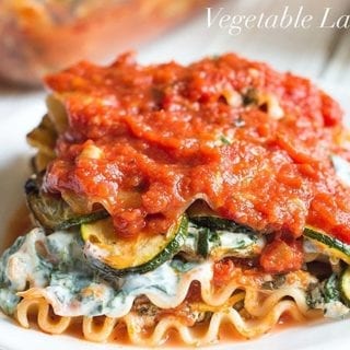 Front view of a section of vegetarian lasagna with veggies and other ingredients visible. A bottle of Bertolli pasta is blurred in the background