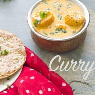 75° View of a Copper Bowl at the Top of the Photo Filled with Yellow cob Curry.