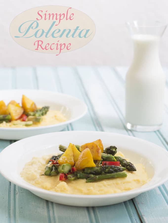 Front View of 1 Plate with Creamy Polenta as the Base. Cooked Golden Beets and Asparagus on the top. In the Background on the right is a Similar Plate But Only 3/4 of it is Visible. A Small Glass Pitcher Filled with Milk is visible of the Left Side of the Background