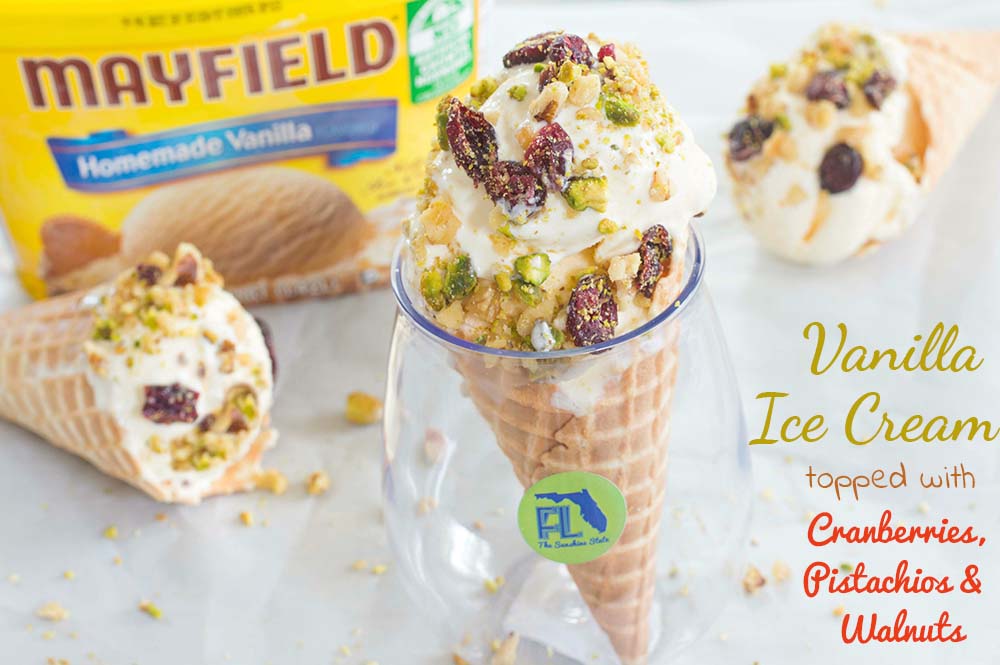 Ice cream cone in a glass and topped with pecans, cranberries With the Mayfield Ice Cream Container in the background
