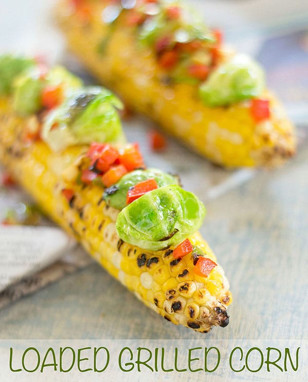 Front view of loaded grilled corn on the cob with brussles sprouts and bell pepper