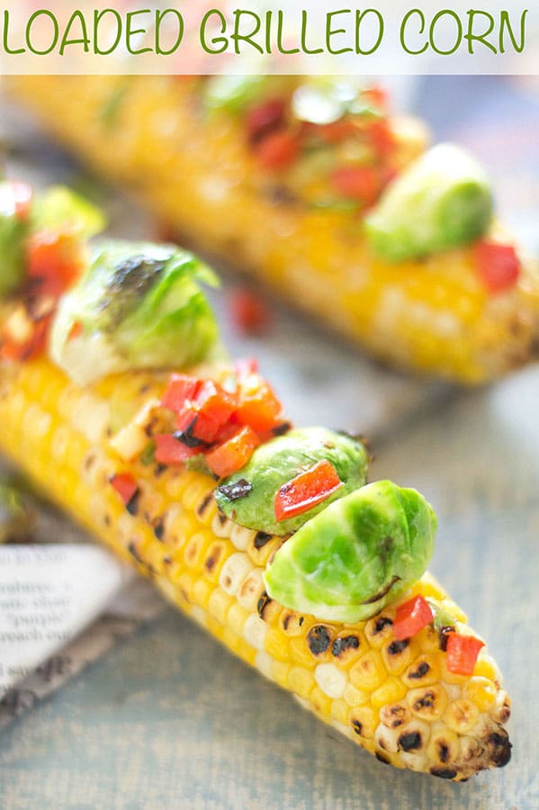 Closeup view of loaded grilled corn on the cob with brussles sprouts and bell pepper